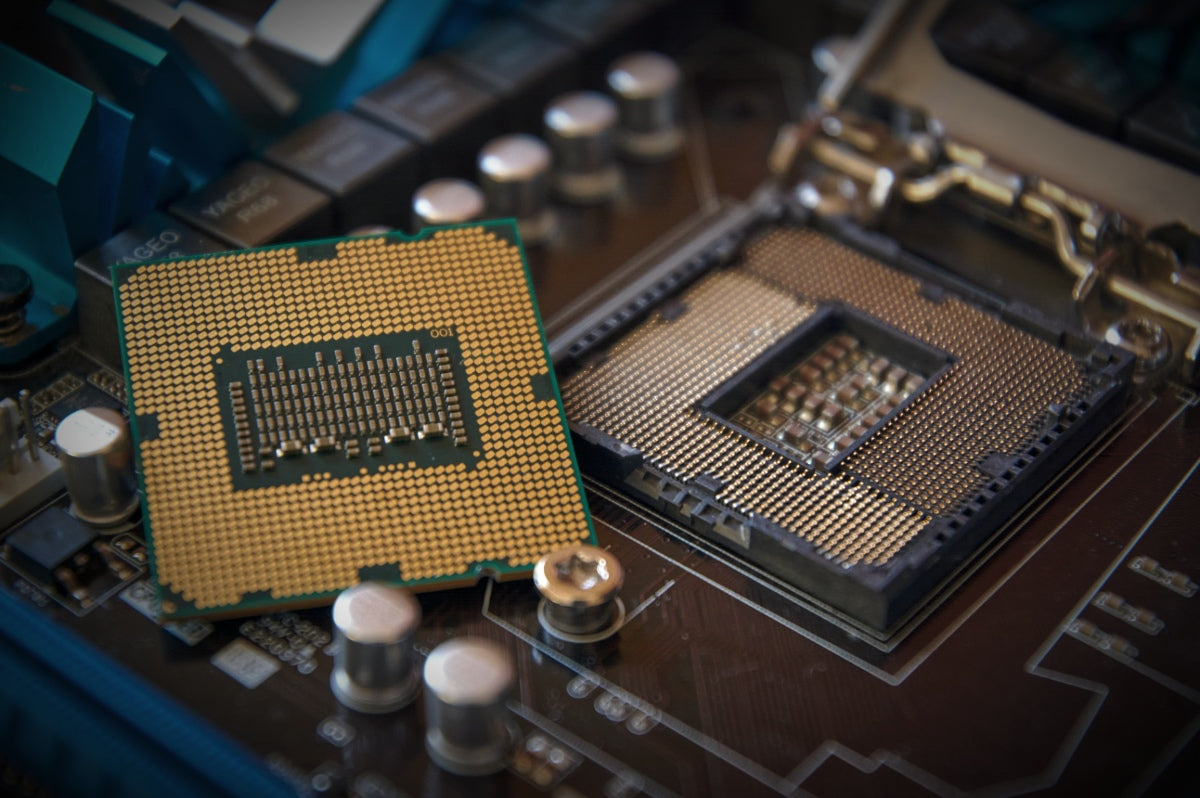 Close-up of a CPU beside a motherboard socket for a custom gaming PC build, showing processor pins and high-performance desktop motherboard hardware.